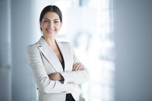 A confident woman in business attire stands with crossed arms, symbolizing professionalism in visa application tracking.