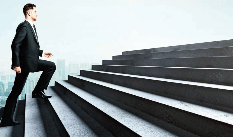 A man in a suit climbs a large staircase against a city skyline backdrop.