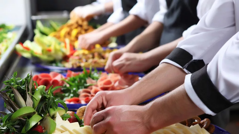 Chefs preparing an assortment of food in a professional kitchen.